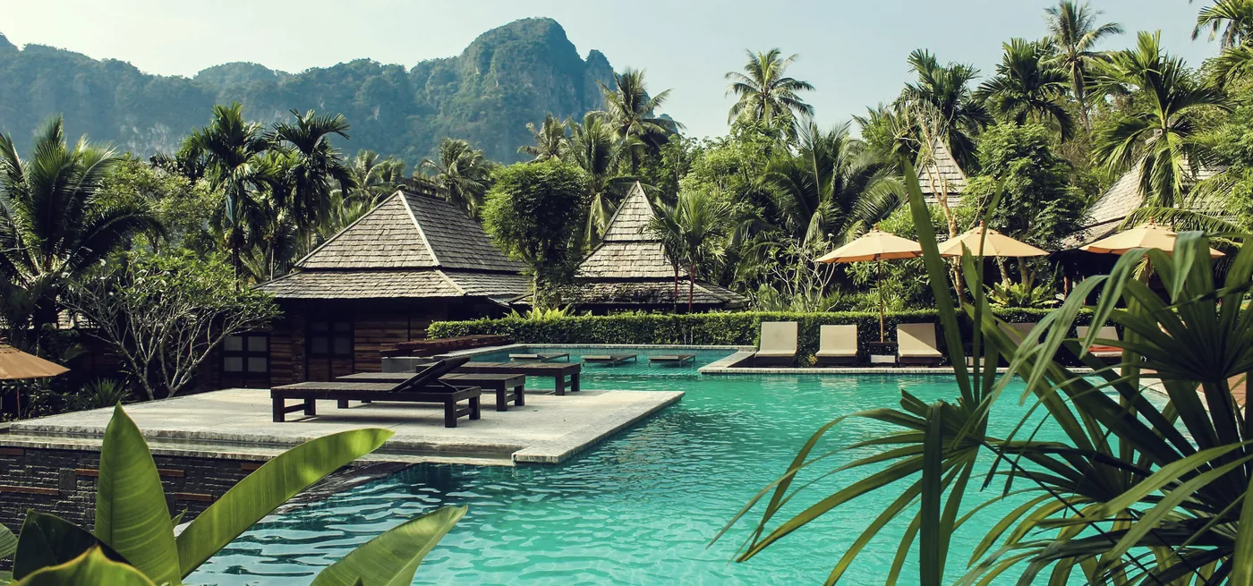 مسبح منتجع محاط بالنخيل وأكواخ ضيافة